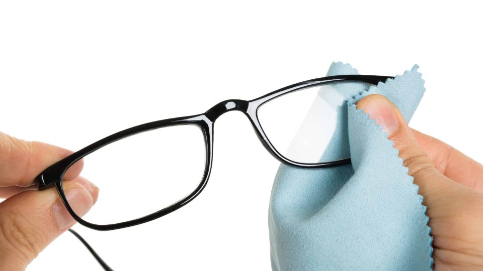 Close-up Of Person's Hand Cleaning Eyeglasses With Cloth