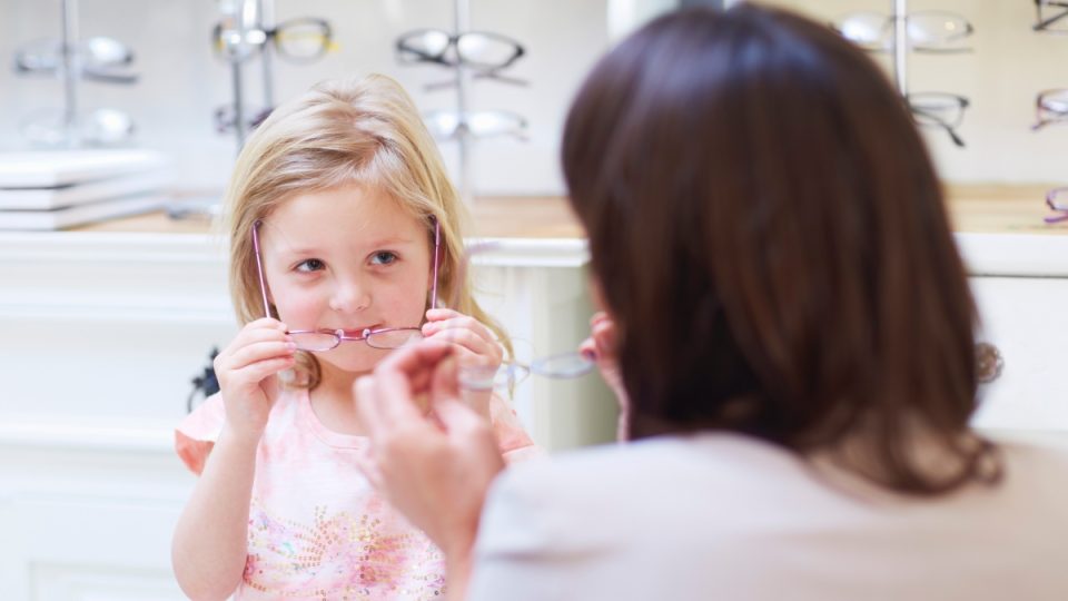 Girl at the optician trying on glasses