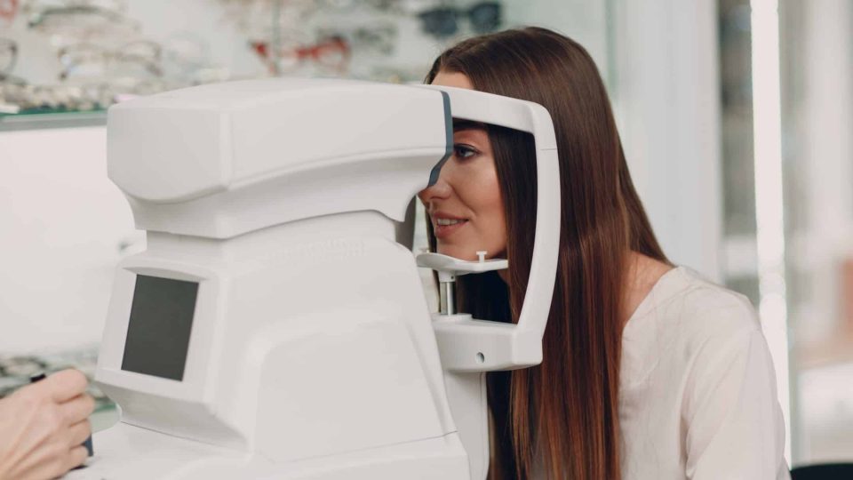 A woman doctor and patient doing opthalmology check vision test refractometer.