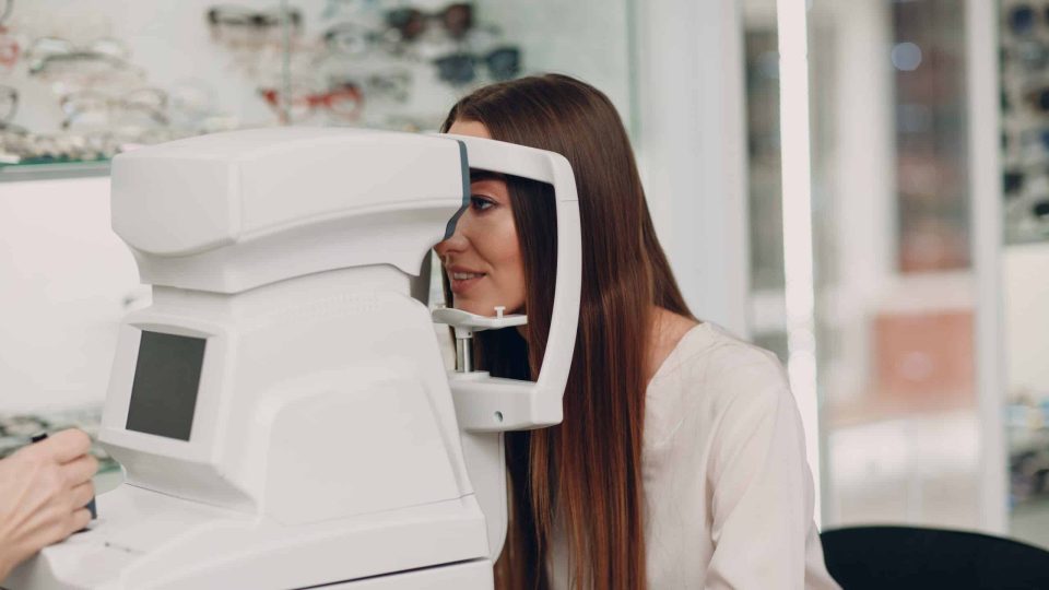 A woman doctor and patient doing opthalmology check vision test refractometer.