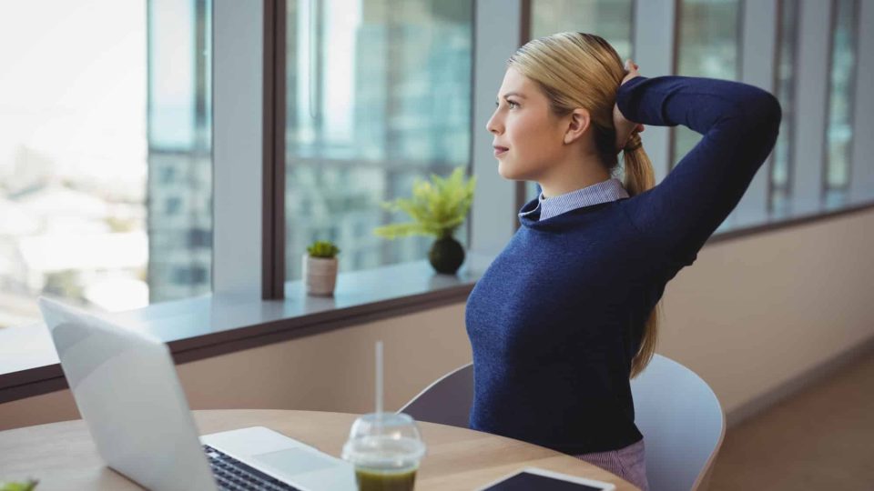 Executive stretching her hands while working in office
